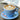 Blue cup of cappuccino with latte art on a saucer, with coffee mate creamer