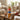 A bottle of Torani Cookie Butter stands on a wooden table in a cozy living room setting, next to a mug of coffee with a cookie on top and a small bowl of cookies. A person's hand is holding the mug.