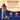 A bottle of Torani Huckleberry syrup displayed on a beige and dark blue graphic background with ingredient text and feature icons. The bottle is a plastic PET bottle with a brown liquid inside featuring a red, yellow, and blue label.