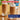 Two tall glasses of iced coffee or latte on woven coaster, topped with whipped cream and sliced almonds, with a bottle of Torani syrup in the background. Promotional text overlays read '33% MORE FLAVOR, for less.