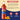 A bottle of Torani Orange syrup shown on a beige and dark blue graphic background with ingredient text, orange slices, and icons for plastic bottle and natural flavor