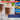 A glass mug filled with a brown beverage topped with whipped cream and cocoa powder, with a blurred bottle of Torani Irish Cream in the background. Promotional text overlays read '33% MORE FLAVOR, FOR LESS.